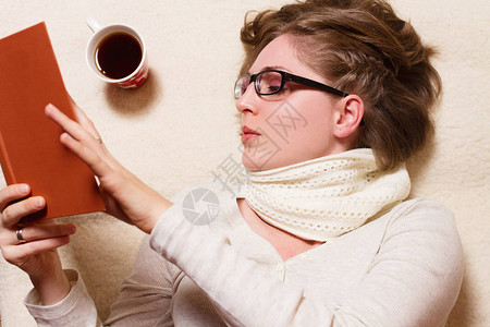 年轻女子看书和喝咖啡或茶的顶视图图片