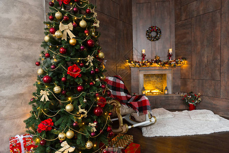 漂亮的配有带毯子的摇椅装饰着现代火焰的壁炉和大圣诞树背景图片