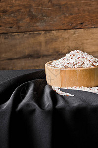 黑色背景木碗中的茉莉花米和糙米图片