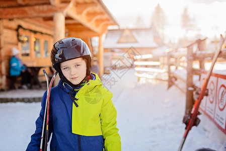 戴着黑色滑雪头盔的孩子拿着滑雪板滑雪胜地冬天的孩子图片