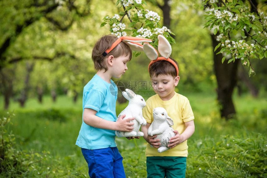 两个小男孩和朋友在春天花园的传统寻蛋活动中图片