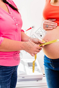 常住孕妇和助产士测量带丝的婴儿撞背景图片