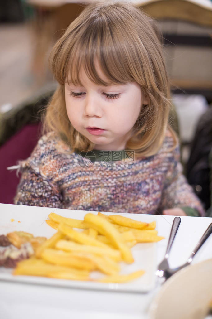 三岁金发可爱的caucasian孩子织毛衣在餐厅吃薯条图片