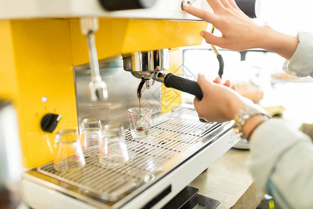 女咖啡师在咖啡店用咖啡机冲泡浓图片