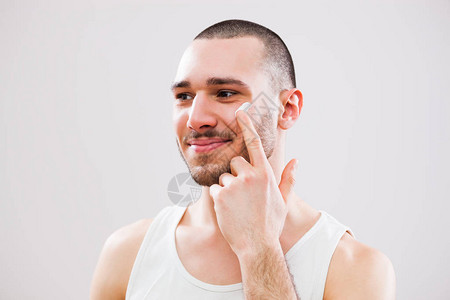 正在脸上涂抹护肤霜的年轻人图片