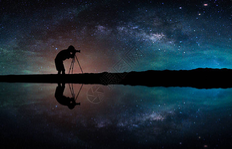 景观与银河系。夜晚的天空，与剪影摄影师拍照在山上图片