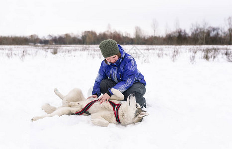 冬天女主人带着哈士奇狗在雪地上玩耍图片