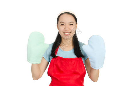 身着红围裙和烤炉手套的亚洲青年妇女准备做饭或烘背景图片