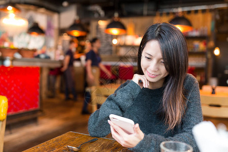 在咖啡店看手机的女人图片