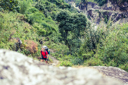 在尼泊尔喜马拉雅山背着包登山的女背包客在高山徒步旅行和徒步旅行安纳普尔纳环线跋涉中的安纳普尔纳喜马尔山脉亚洲背景图片