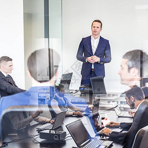 成功的团队领导和企业主在公司办公室领导商务会议在前景和玻璃反射的笔记本电脑上工作的商务人士商背景图片