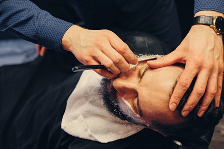 理发师用锋利的钢剃刀刮一个人图片