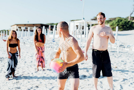 一群千百年的朋友在海滩上玩沙滩球活动图片