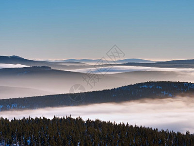 冬天山的迷雾笼罩的山谷奶油薄雾之上的山峰图片