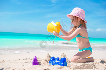 在热带度假期间玩沙滩玩具的小女孩图片