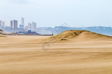沙滩对沙丘植被和城市天图片