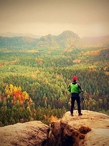 摄影师在岩石峰顶上使用相机和三脚架图片
