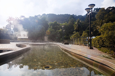 含有蒸汽泉和太阳的天然温泉火山岩流矿泉水池图片