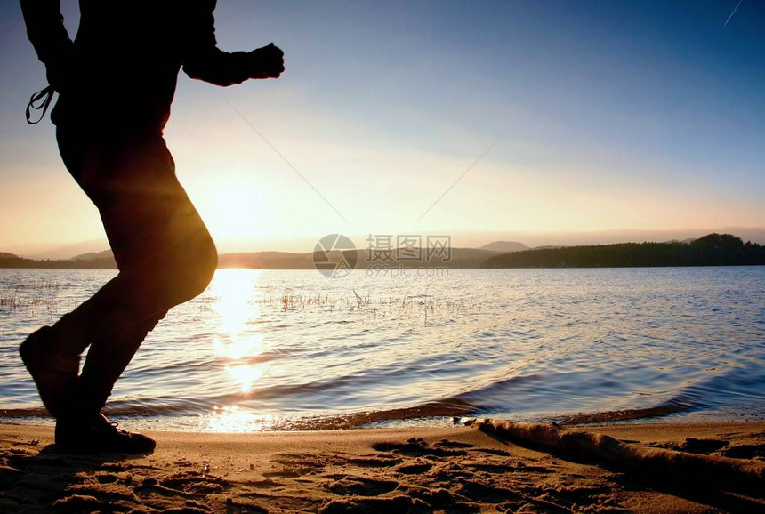 运动活跃男子在日落时在海岸线上跑步图片