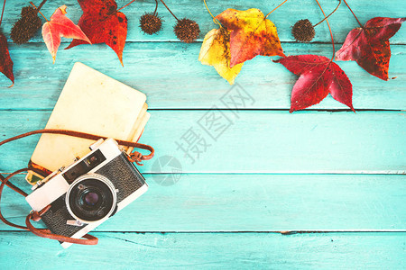 复古相机和空的旧即时纸相册在木桌上与枫叶在秋季边框设计秋季纪念和怀旧的概念背景图片