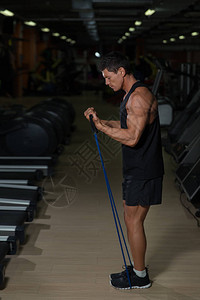 健身男子在健身房里用弹力带锻炼肌肉男子用弹橡皮筋锻图片