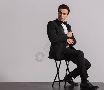 一个坐着优雅男子的侧面修补他的袖子仰视灰图片