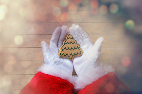 圣诞老人拿着Chrstmas饼干在木头背景图片