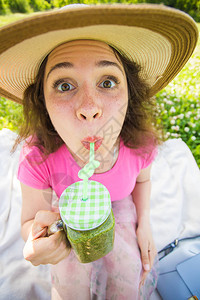 有趣的女人在野外餐时喝绿色解毒滑冰水面对户图片