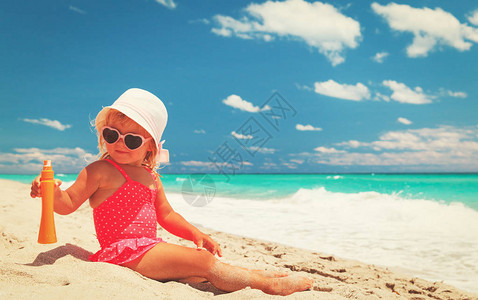 防晒防晒霜在海滩的小女孩图片