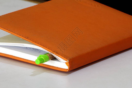 橙色笔记本和笔的照片图片