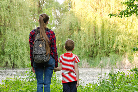 母亲和儿子站在湖和森林的背面图片