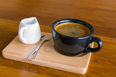 黑色蓝咖啡杯加美式咖啡勺子和木桌背景图片
