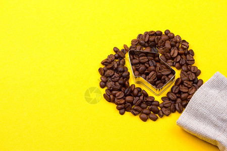 黄色背景上箭头形状的咖啡豆背景图片