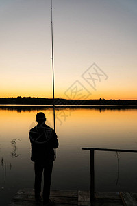 日落时一个男人在码头钓鱼图片