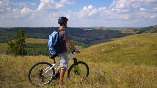 骑自行车的年轻人从绿色山上滚下来向图片