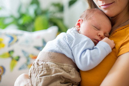 年轻母亲轻地抱着她新生的男婴图片