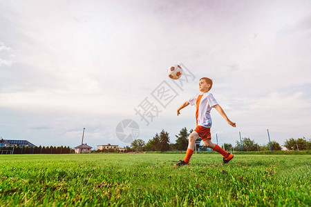 男孩在球场上玩足球儿童踢足球白色红图片