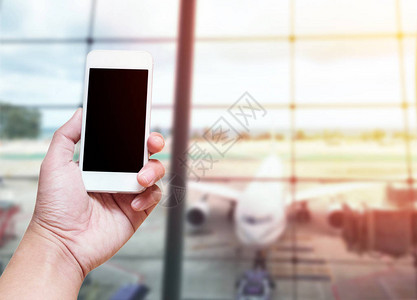 手持智能手机的空屏幕模糊照片机场航站楼背景与手机屏幕图片