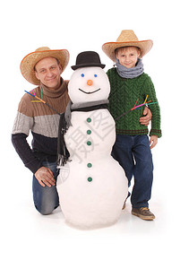 父亲和儿子与雪人围巾和帽图片