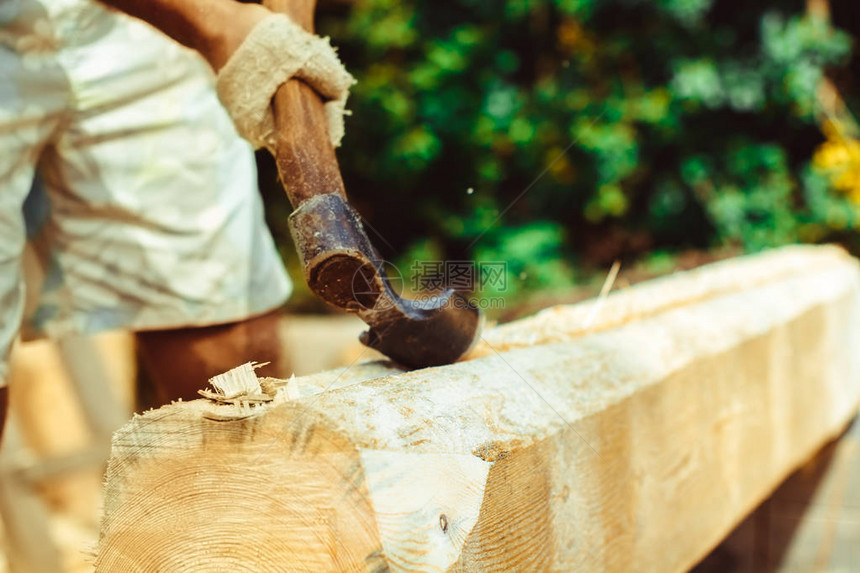 一个强壮男人用把木头砍碎的手集中在斧子上当它分图片