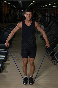 健身男子在健身房里用弹力带锻炼肌肉运动男子用弹橡皮筋锻图片