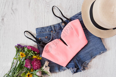 粉色上衣牛仔短裤帽子和野花束时尚概念图片