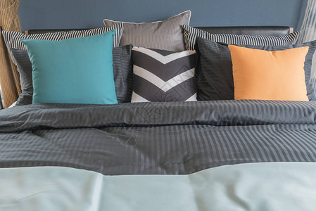 现代卧室深色床上的彩色床枕头室图片