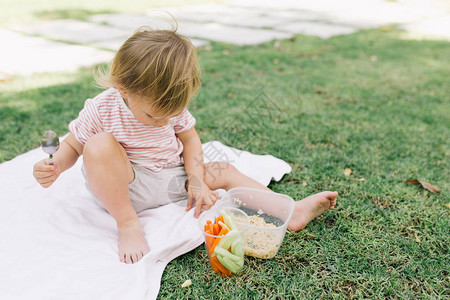 可爱的女婴在户外吃粥和蔬菜的肖像图片