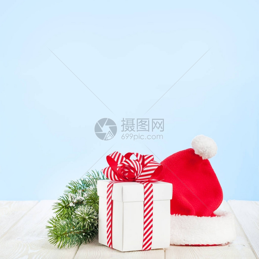 圣诞礼品箱圣塔帽和木桌上的fir树枝图片