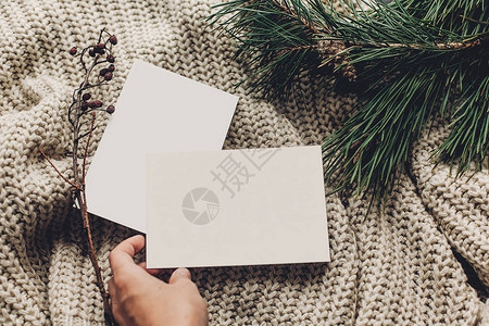 手拿着时尚针织毛衣背景上的空圣诞贺卡图片