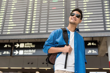 亚洲旅客在现代机场检查航班信息屏幕图片
