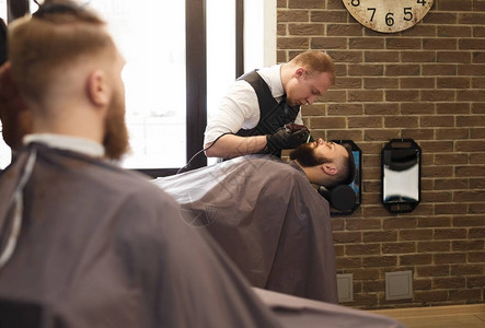 男发廊的时髦理发师在理发店用图片