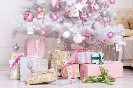 礼品盒粉色和白色圣诞装饰球挂在一棵装饰白色圣诞树上概念图片