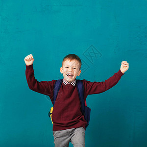 带着大背包跳起来的快乐微笑的小男孩背景图片